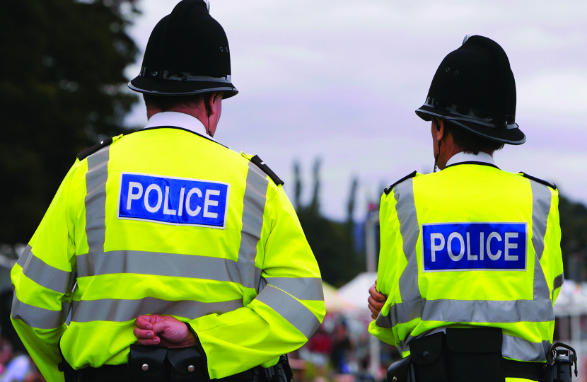 Two police officers pictured with their backs to the camera. They are wearing high vis jackets with "POLICE" written across their backs.